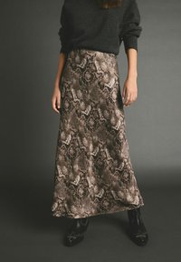 Maxi nederdel med slangeprint i brune og sorte nuancer. Lavet af et glat stof med et flydende design. Båret med sorte ankelstøvler.