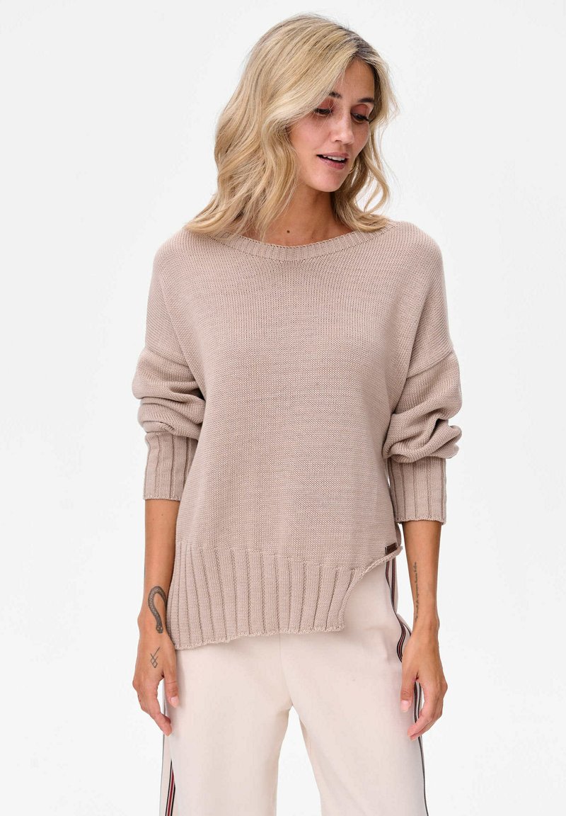 Beżowy sweter z dzianiny o szerokim dekolcie, z prążkowanymi mankietami i dołem. Oferuje luźny krój z subtelnymi bocznymi rozcięciami. Gładka tekstura.