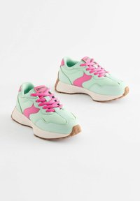 Miętowe sneakersy z różowymi akcentami, z teksturowaną podeszwą i kontrastującymi sznurowadłami. Miękki materiał i sportowy design z zakrzywionymi liniami.