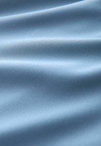 Tissu bleu clair lisse avec des plis doux et une texture tendre, présenté en gros plan.