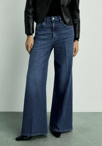 Široke jeans hlače v temno modri barvi, z visokim pasom, klasičnim pet-pocket dizajnom in čistim zaključkom na robu.