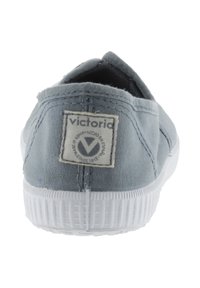 Lysblå lærredsko med en hvid gummisål. Har et stofmærke bagpå med brandnavnet 'victoria' og et logo.