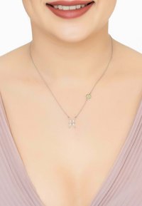 Silver necklace with a Pisces symbol, adorned with small gemstones. Chain is delicate and minimalistic, complementing the neckline.