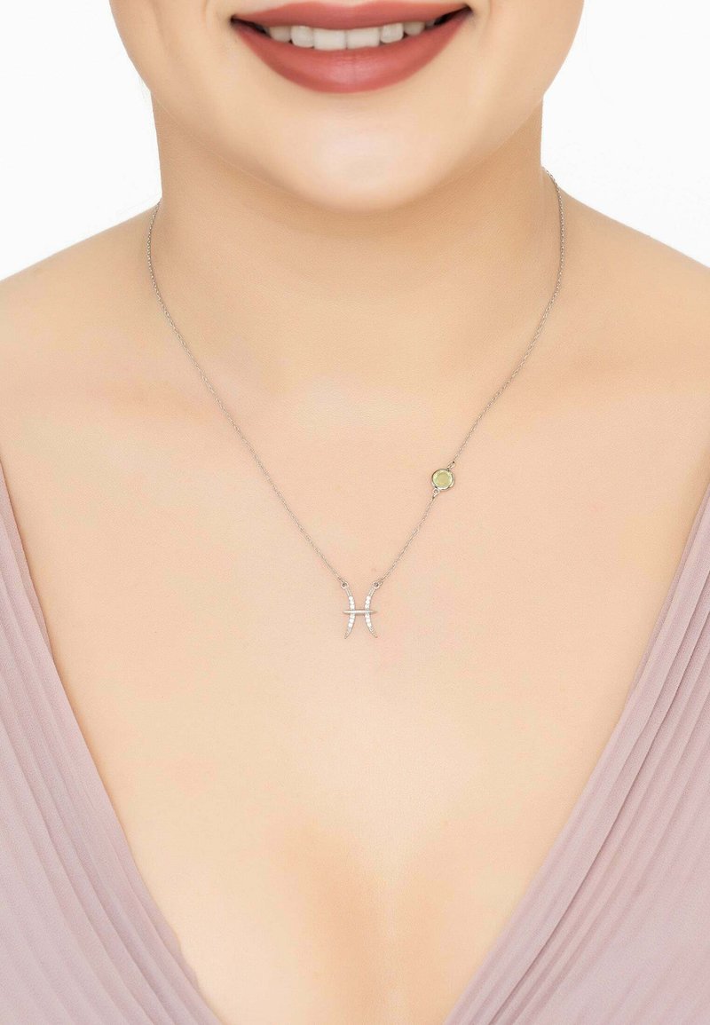 Silver necklace with a Pisces symbol, adorned with small gemstones. Chain is delicate and minimalistic, complementing the neckline.