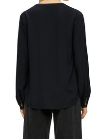 Blusa nera a maniche lunghe con scollatura rotonda, tessuto liscio, vestibilità comoda e polsini con bottoni. Leggero luccichio e leggero drappeggio.