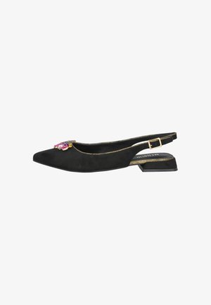 Zapato plano de ante negro con talón descubierto, puntera puntiaguda, ribete dorado, decoración con piedras preciosas rosas y moradas, y correa ajustable con hebilla dorada.