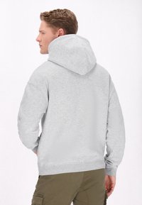 Felpa grigia con cappuccio, dal tocco morbido, con polsini e orlo a coste, vista dal retro, abbinata a pantaloni cargo verde oliva.