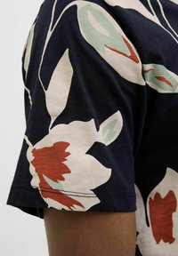 Jūrinio stiliaus marškiniai su gėlių raštu, išryškinančiais dideles baltas ir raudonas gėles su žaliais akcentais, pagaminti iš tekstūruoto audinio, su trumpomis rankovėmis ir laisvu fasonu.