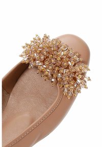 Zapato plano de cuero color beige con un interior texturizado y un grupo decorativo de cuentas doradas y de cristal en la puntera.