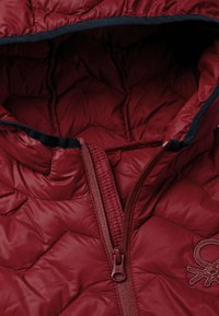 Chaqueta acolchada burdeos con un patrón de acolchado, que cuenta con un cierre de cremallera y ribetes en azul oscuro a lo largo de la capucha y la cremallera.