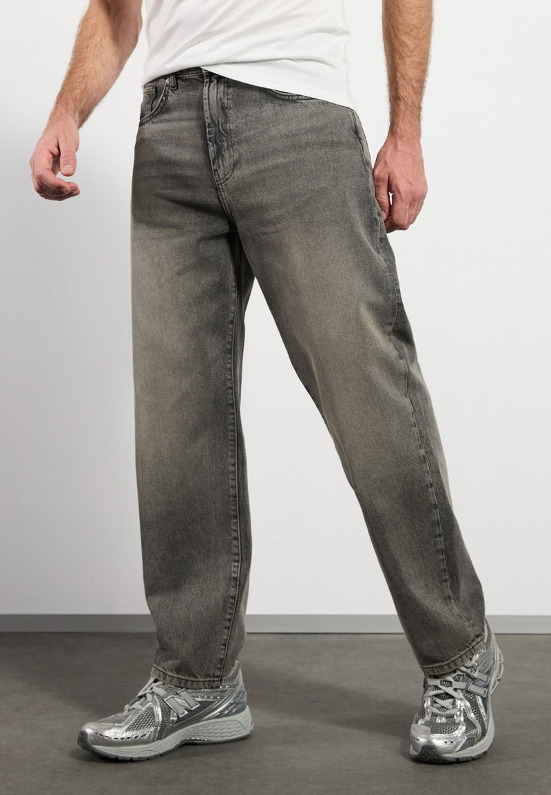 Gray denim jeans with a straight-leg fit, featuring a faded texture and five-pocket design, paired with silver athletic shoes.