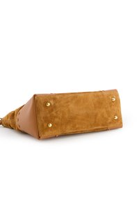 Sac à main en suède et cuir beige avec des bords lisses, des clous en acier doré et une finition légèrement texturée.