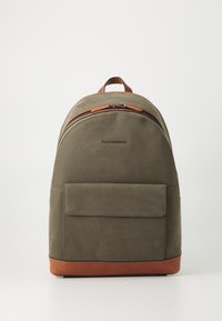 Kaki ryggsekk med brun lærbunn og detaljer, med en jevn tekstur, buet design og en frontlomme med klaffelukking.