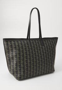 Stor sort totebag i teksturert materiale med et geometrisk mønster i lys grå. Glatte håndtak og åpen toppdesign.