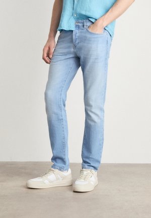Jeans in denim azzurro chiaro con taglio dritto, dotati di cinque tasche e leggere sfumature. Abbinati a sneakers bianche e beige.