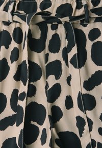 Tessuto beige con un motivo leopardato nero, dotato di una cintura annodata e di un design plissettato con dettagli di cucitura a contrasto.