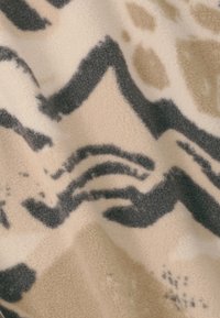 Tissu en polaire avec un motif abstrait aux nuances de beige, noir et marron. Texture douce avec des lignes ondulées distinctes et des taches.