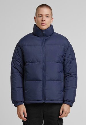 Navy puffer jacket with high collar, zip front, and elastic cuffs. Features stitched panels and a smooth, shiny texture.