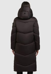 Musta toppatakki hupulla, jossa on siksak-kuvio, sileä kangas ja pitkä malli, näkyvillä ompelusaumoilla ja lisänä koristeellinen nappi.