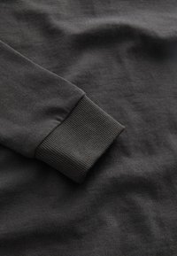 Dunkelgraues Langarmshirt mit gerippten Bündchen und einer glatten, weichen Textur, mit minimal sichtbaren Nähten und ohne Muster.