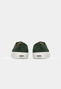 Grüne Wildleder-Slipper mit weißer Gummisohle und Logodetail an der Ferse. Glatte Textur mit rundem Rückendesign.