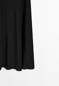 Zwarte stoffen rok met een gladde textuur, vloeiend ontwerp en een zoom die zachtjes buigt. Eenvoudig en elegant zonder extra patronen of accenten.