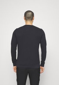Felpa a maniche lunghe navy realizzata in tessuto morbido, con colletto a girocollo a coste, polsini e orlo, e un logo discreto sul retro.