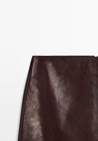 Burgunderrote Lederrock mit glatter Textur, geradem Schnitt und sauberen Kanten. Verfügt über minimale Nähte und ein elegantes Finish.