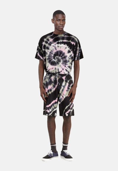 Sort og pastelfarvet tie-dye t-shirt og shorts sæt, der har rund hals, afslappet pasform og snøre i taljen, parret med marineblå sneakers.
