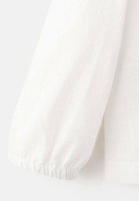 Dolg bel beli rokav z nabiranim manšetom, izdelan iz teksturirane tkanine; vsebuje subtilne navpične črte in mehke, lahke videz.