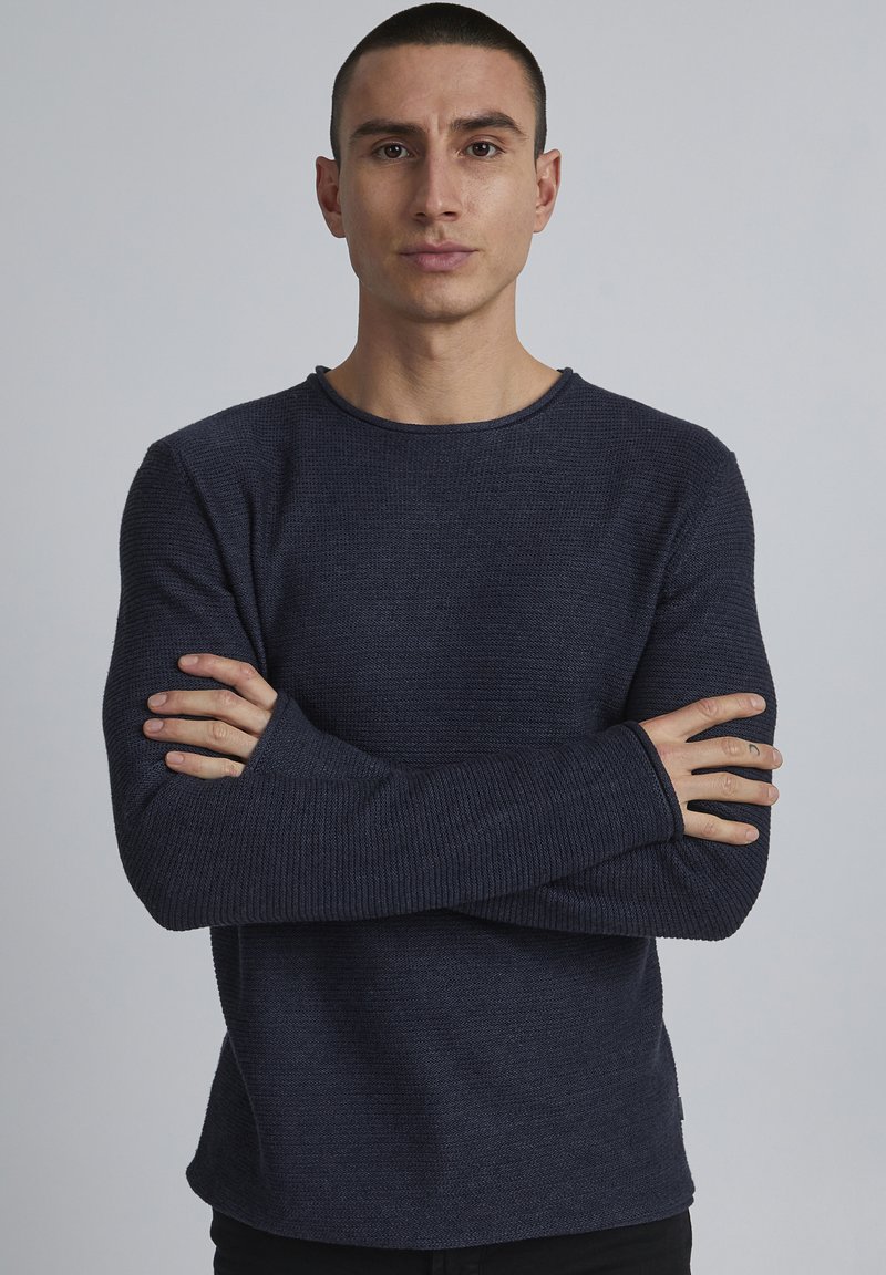 Navyblaues, gestricktes Langarmshirt mit strukturiertem Finish, Rundhalsausschnitt und leicht lockerer Passform. Verfügt über verlängerte Bündchen für zusätzlichen Komfort.