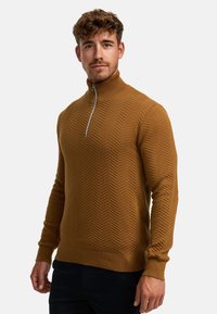 Bronse zip-up genser med et strukturert herringbone-mønster, ribbestrikkede mansjetter og søm, laget av mykt strikkemateriale.