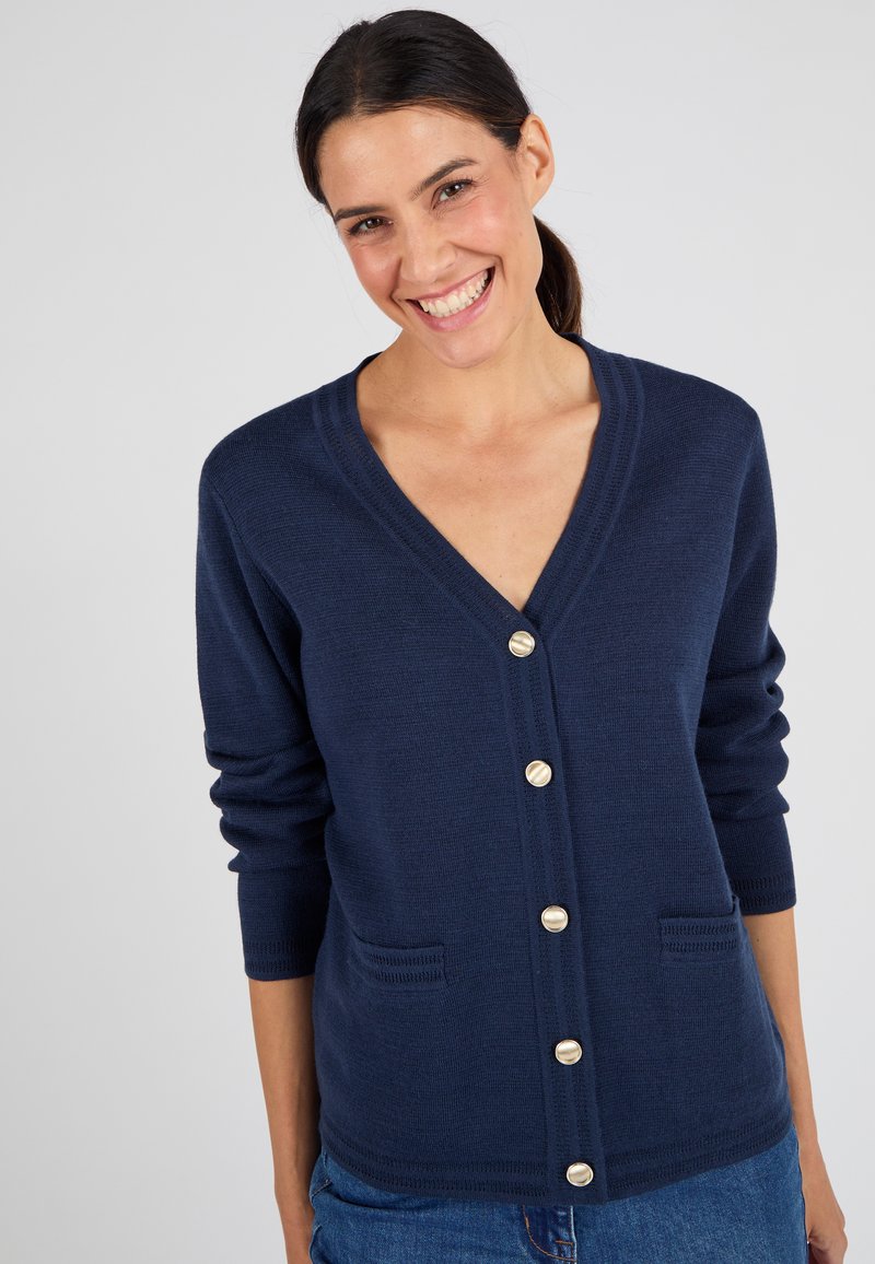 Cardigan bleu marine avec un décolleté en V, des boutons dorés et une texture tricotée. Présente deux poches avant et des manches longues.