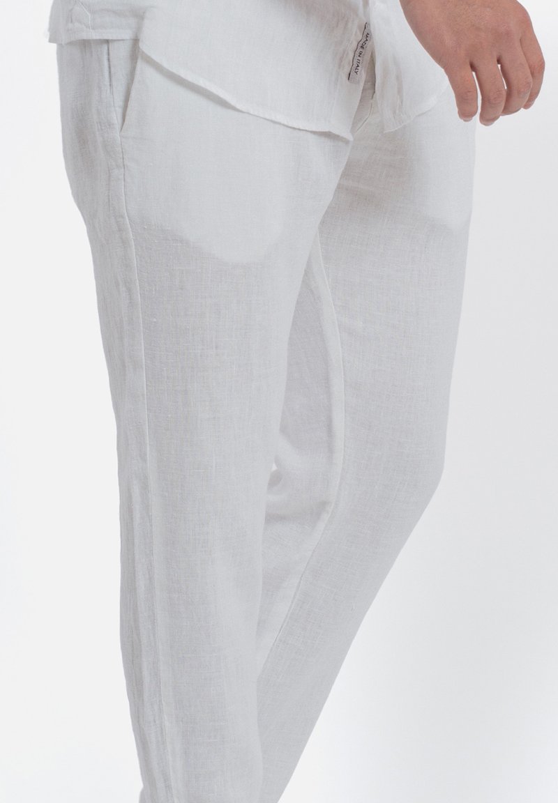 Witte linnen broek met een gladde textuur, met een rechte snit en zijzakken, gepresenteerd tegen een effen achtergrond.