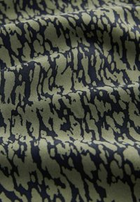 Tissu vert olive avec motif léopard noir irrégulier, légèrement froissé pour montrer la texture et la douceur.