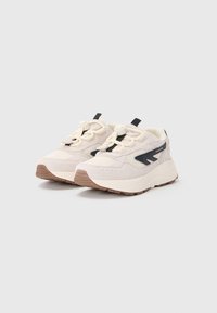 Lys beige treningssko med svarte detaljer, teksturert syntetisk og mesh-overdel, polstret såle og en dratthandler ved hælen.