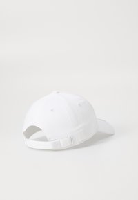 Hvid baseballcap med en buet skygge, lavet af stof. Har en justerbar strop bagpå og en diskret logo detalje.