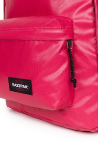 Jasnoróżowy plecak Eastpak o teksturowanym wykończeniu, z przednią kieszenią, czarnym okablowaniem i czarną etykietą z logo.