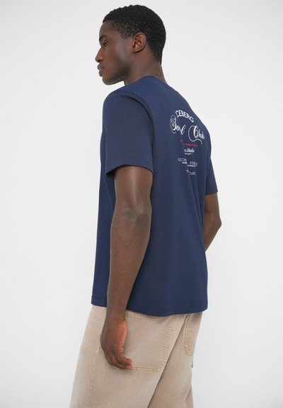 T-shirt bleu marine à manches courtes avec un motif graphique au dos. Encolure ronde, matière en coton doux et coupe décontractée.