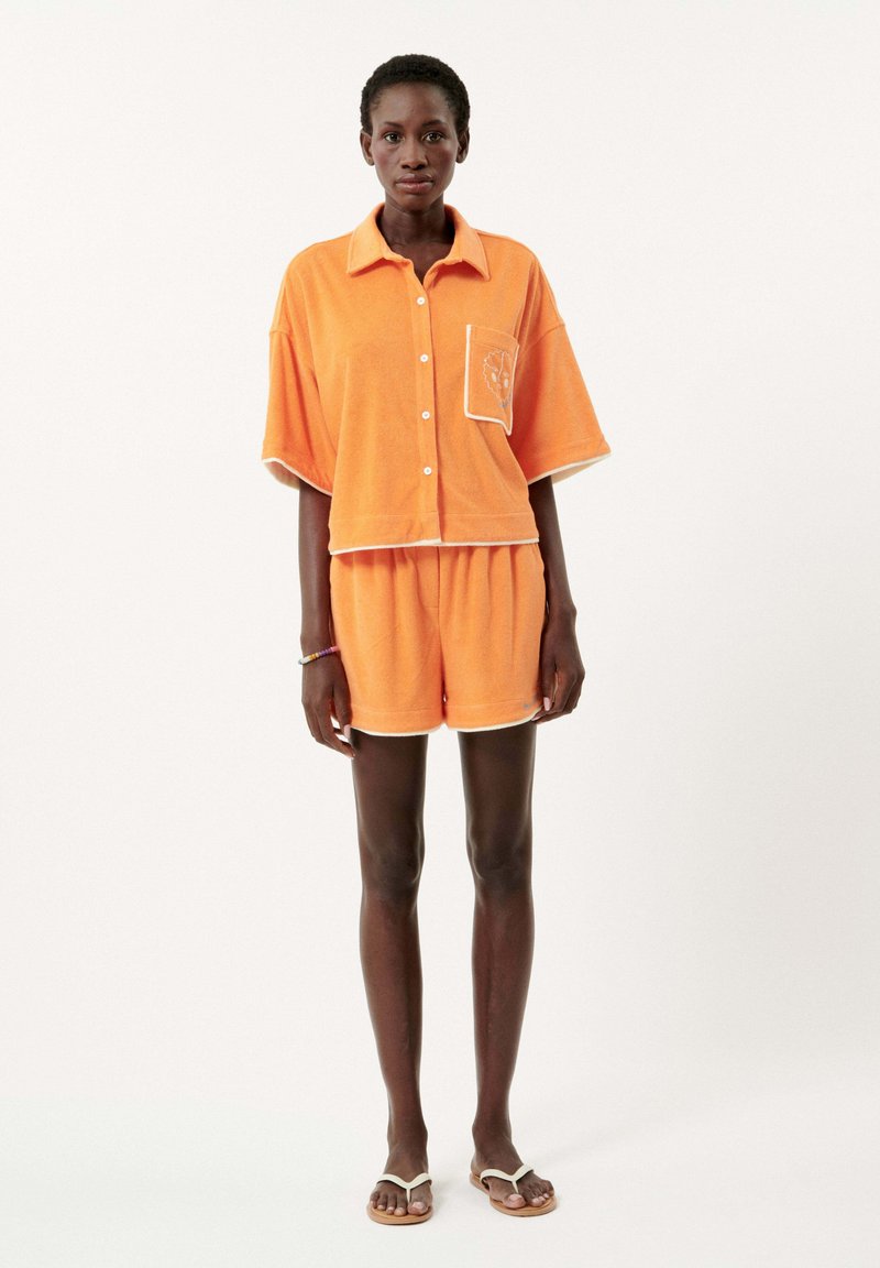Oranje badstof matching set bestaande uit een kortmouwige button-up top en shorts, met contrasterend witte afwerking en een ontwerp van een borstzak.