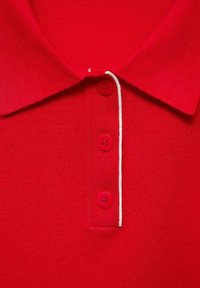 Rød polo-shirt med en tekstureret stof, standard krave og tre knapper i matchende rød, pyntet med hvide syninger langs halsudskæringen.