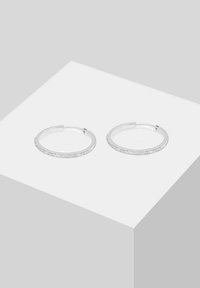 Cerceii rotunzi din argint au un design subțire, cu un rând de pietre clare pe marginea exterioară, evidențiind un finisaj elegant și strălucitor.