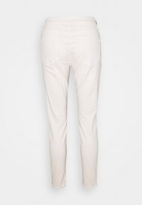 Jean en coton blanc avec une coupe ajustée, présentant une taille mi-haute, deux poches arrière et une texture lisse.