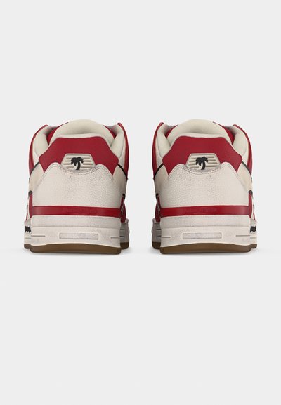 Ζευγάρι λευκά και κόκκινα αθλητικά παπούτσια με μπεζ σόλες, φτιαγμένα από πίσω, με ένα μικρό μαύρο λογότυπο φοίνικα σε κάθε φτέρνα.