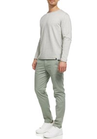 Jasnoszara bluza z długim rękawem o subtelnej fakturze, zestawiona z miętowozielonymi spodniami o slim fit i białymi trampkami. Prosty design, brak widocznych wzorów.