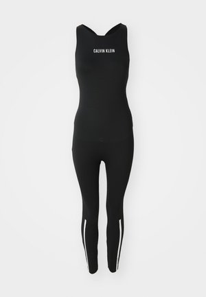 Mono negro con escote redondeado, que presenta un logo blanco de Calvin Klein. Tiene un diseño ajustado y rayas blancas en los laterales de las piernas.