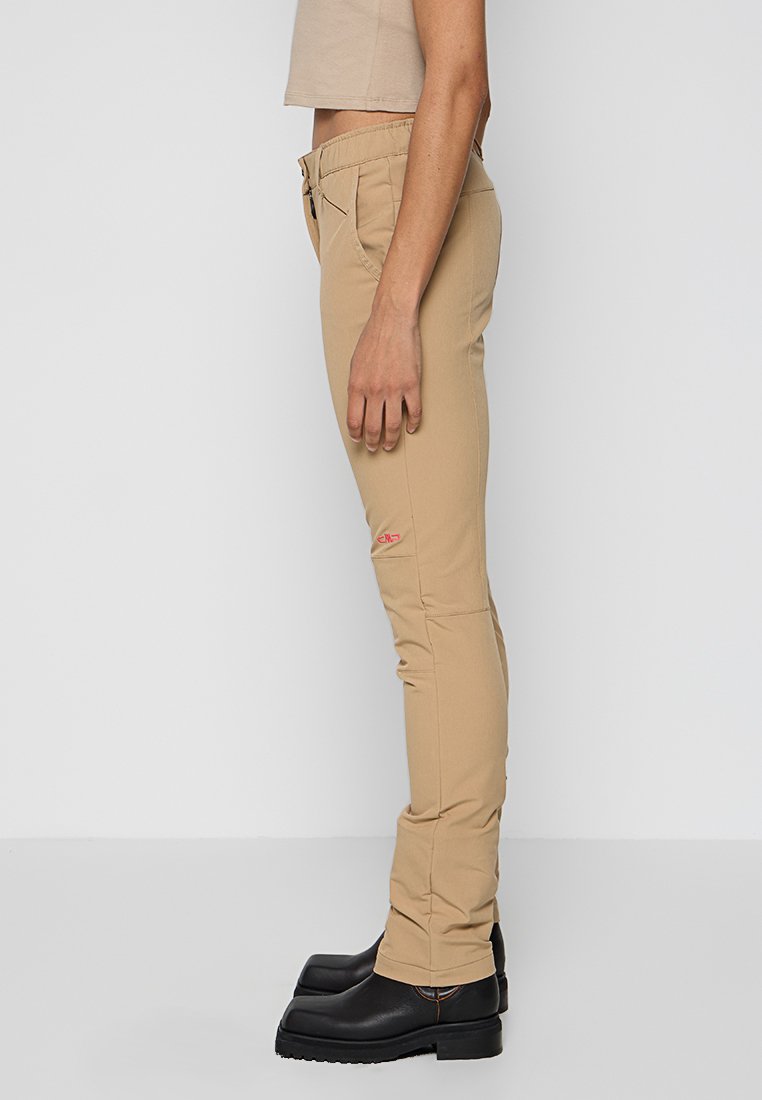 Beżowe spodnie slim fit o teksturowanym wykończeniu, z kieszenią na zamek błyskawiczny z boku i małym czerwonym logo. W połączeniu z czarnymi botkami na platformie.