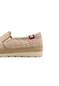 Espadrilles beige intrecciate con superficie testurizzata, dotate di una patch rossa con logo e suola in gomma di colore chiaro. Design classico senza lacci.