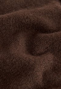 Soft, textured brown fabric with visible fibers and subtle folds, suggesting warmth and comfort.