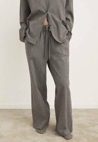 Completo loungewear grigio e nero con motivo a scacchi, composto da una camicia ampia con spacco anteriore e pantaloni a vita elastica con dettagli di coulisse.